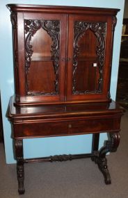 High style mahogany Victorian bookcase/ secretary. Two doors with elaborate rose and trellis carving, slide out top with leather and center drawer supported by rococo carved legs with carved stretcher between them; 38 1/2" w., 64 1/2" h.