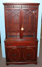 Mid twentieth century mahogany China cabinet. Small cabinet with two glass doors having simple gothic, arch design on doors, drawer over two oval panel doors; 35 1/2" w., 16" d., 69" h.