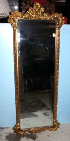 Gold mirror in the rococo style. Fancy gold mirror with C scrolls and flowers. 22" w., 56 1/2" h.