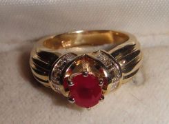 One stamped 14KT yellow gold lady's cast ruby and diamond ring with a ribbed shank with a bright polish finish. Containing: One prong set oval standard brilliant cut natural ruby, measuring 6.20 x 5.18 x 3.50mm, 12% bulge factor, approximate wei