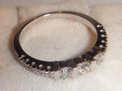 One stamped 14KT white gold lady's cast diamond band with a flat tapered shank with a bright polish finish. Containing: Three channel set round brilliant cut diamonds, measuring 3.16-3.10 x 1.88mm (depth est.) approximate total weight of 3 Stone