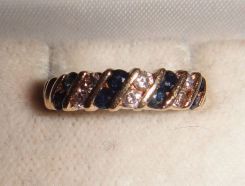One stamped 14KT yellow gold lady's cast sapphire and diamond band with a tapered shank with a bright polish finish. Containing: Eight channel set round standard brilliant cut natural blue sapphires, measuring 2.30-2.10 x 1.43mm, 10% bulge facto