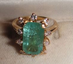 One 10-14KT yellow gold lady's cast emerald and diamond ring with a tapered shank with a bright polish finish. Containing: One prong set emerald standard step cut natural emerald, measuring 11.61 x 7.12 x 4.63mm, 10% bulge factor, approximate we